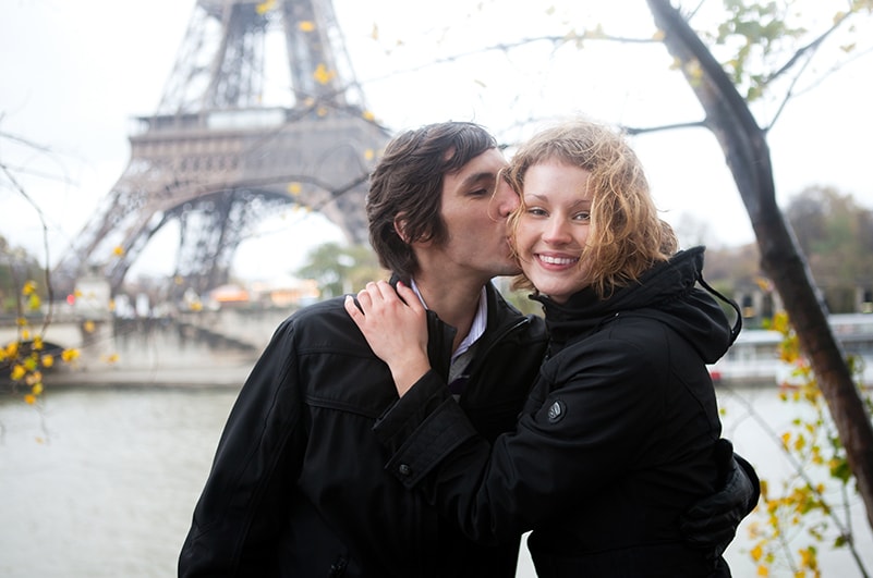Un homme embrasse une femme devant la Tour Eiffel